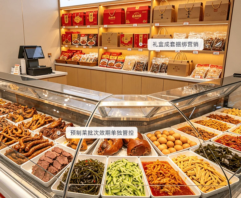 真空礼盒与团餐预制复合场景：后墙木质层架陈列红色卤味礼盒与手提纸袋，前场弧形玻璃展柜分格陈列卤鸭脖、卤猪蹄、卤牛肉、卤蛋与凉拌菜，柜台配置收银设备，配套礼盒成套捆绑营销与预制菜批次效期单独管控